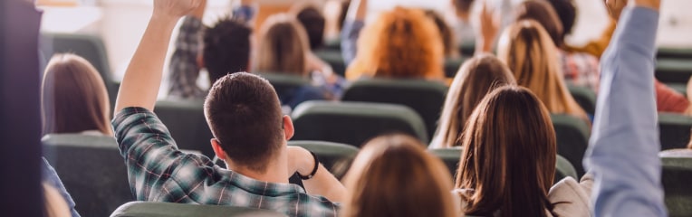 Students in lecture hall some with hands up